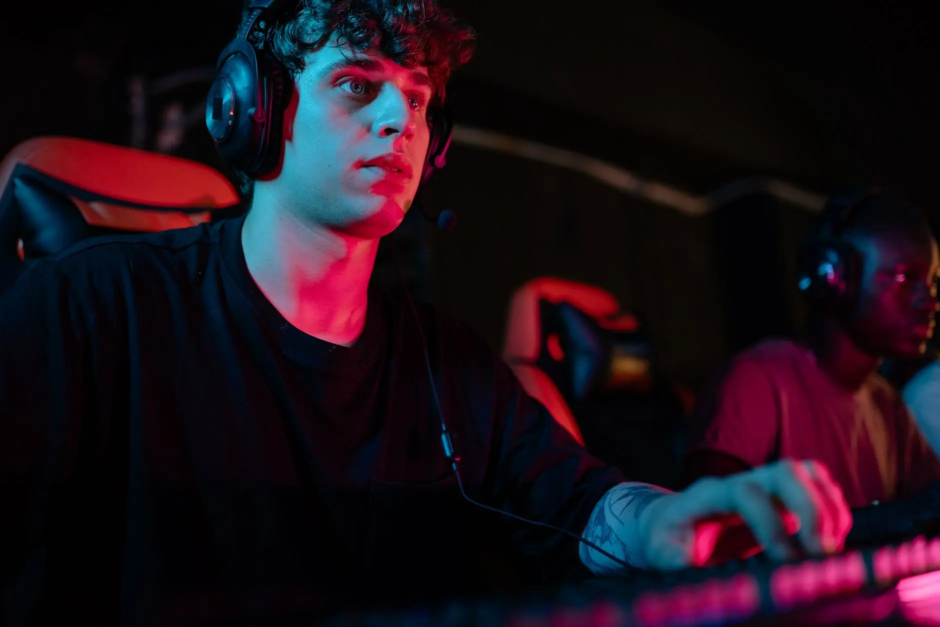 Intense scene of a gamer wearing headphones, focused on gameplay at night.