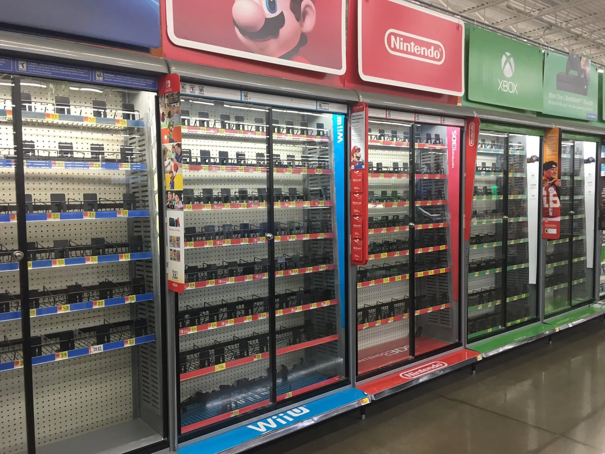 Empty video game shelves in a store showcasing Nintendo and Xbox branding.