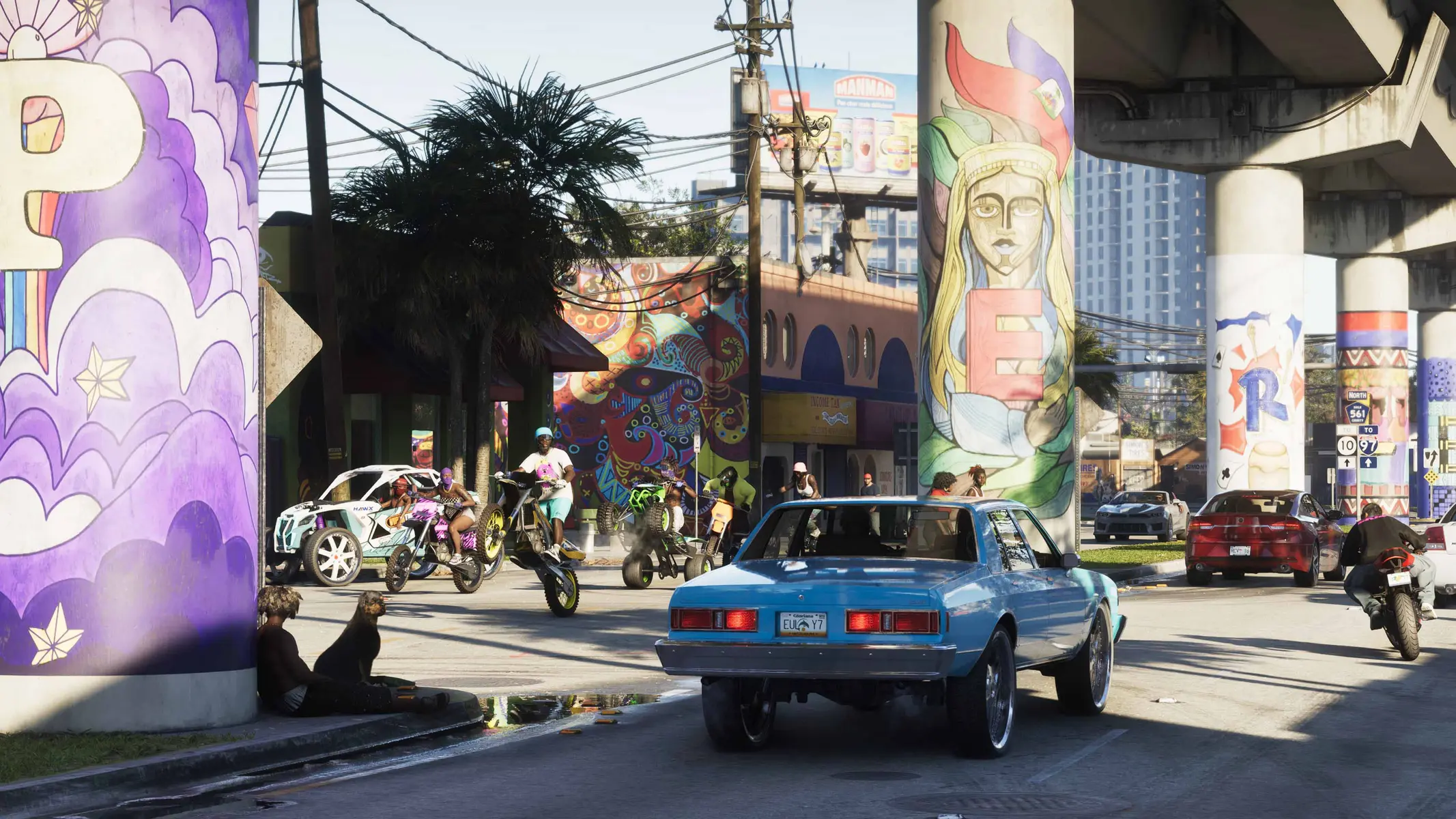A light blue classic car on a vibrant city street with graffiti-covered pillars and people on motorcycles.