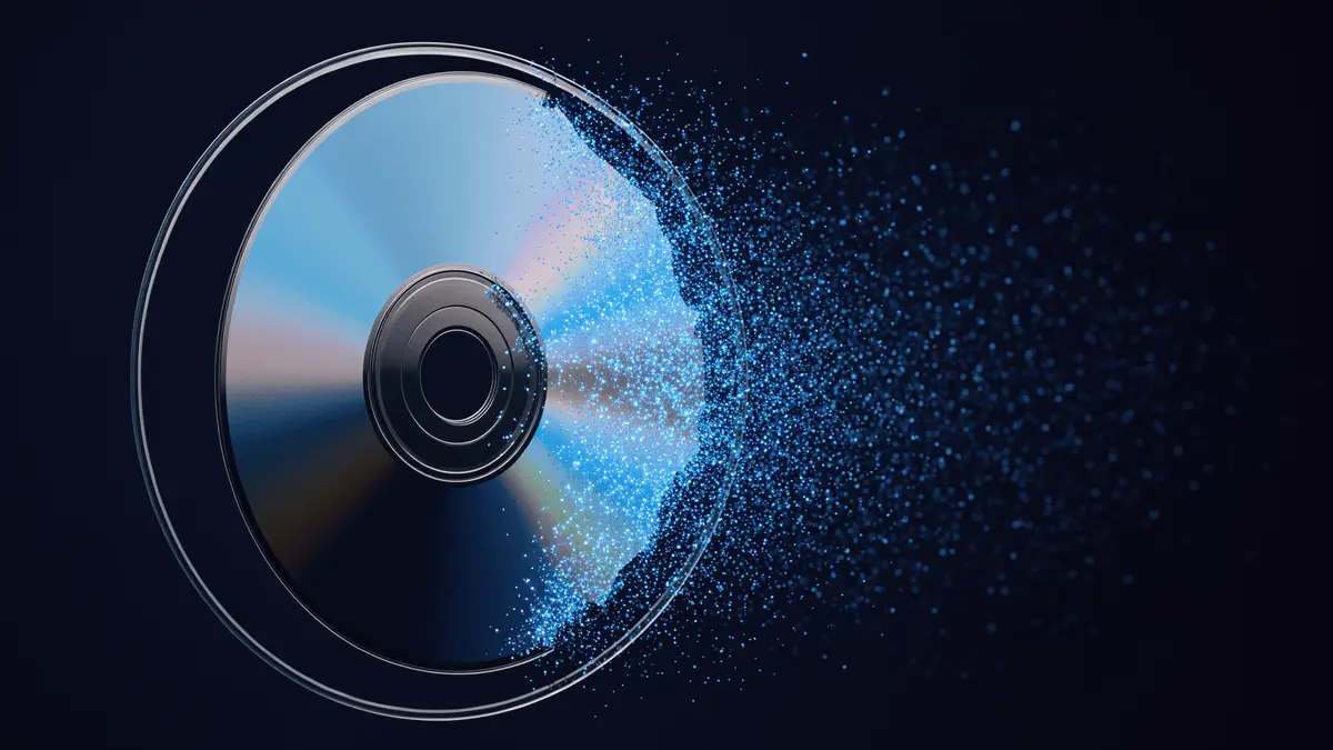 PlayStation game disc dissolving into digital particles against dark blue background