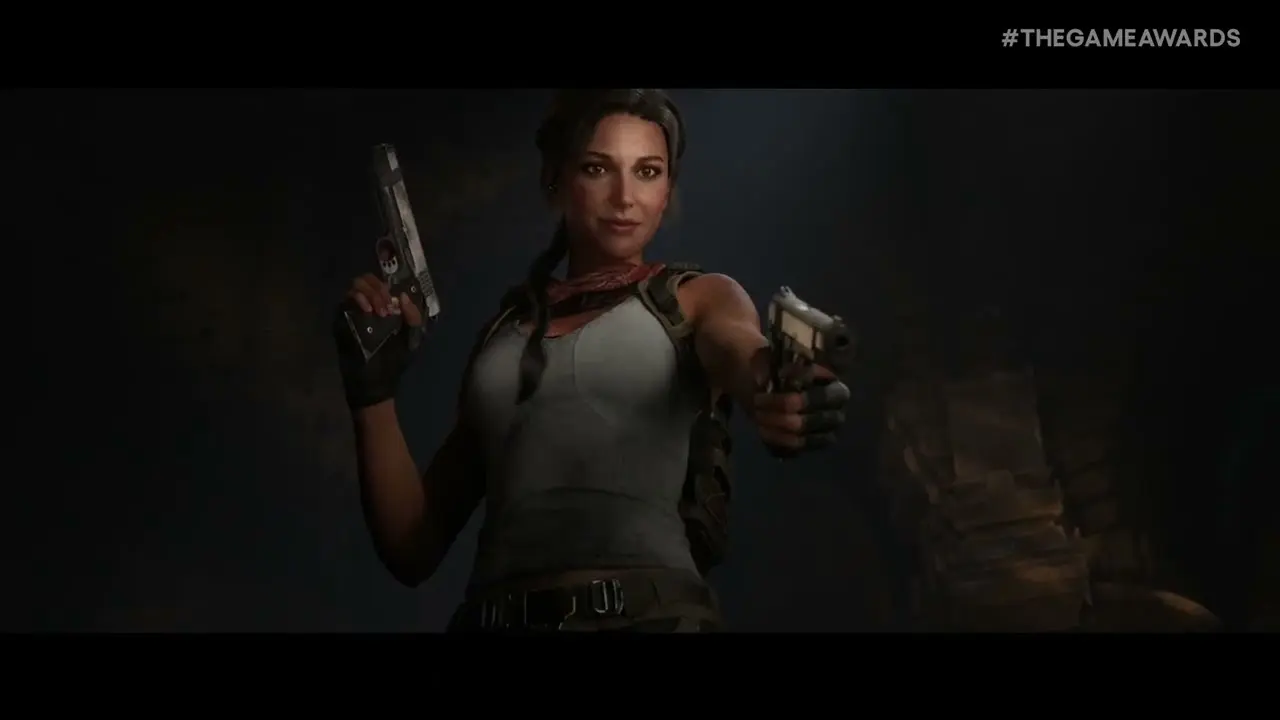 Lara Croft holding two pistols in a dark cavern, with #THEGAMEAWARDS text in the upper right corner