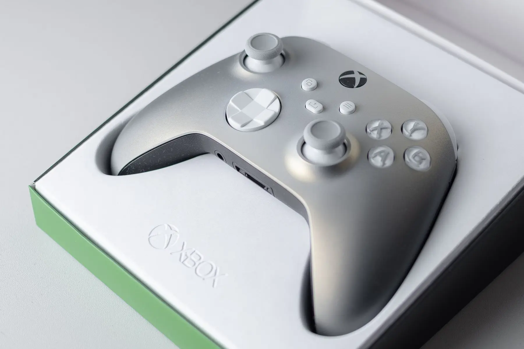 A silver Xbox Series X controller resting in its original white and green packaging