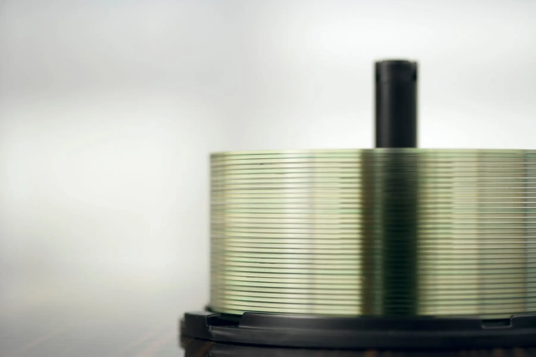 A stack of blank compact discs on a black spindle