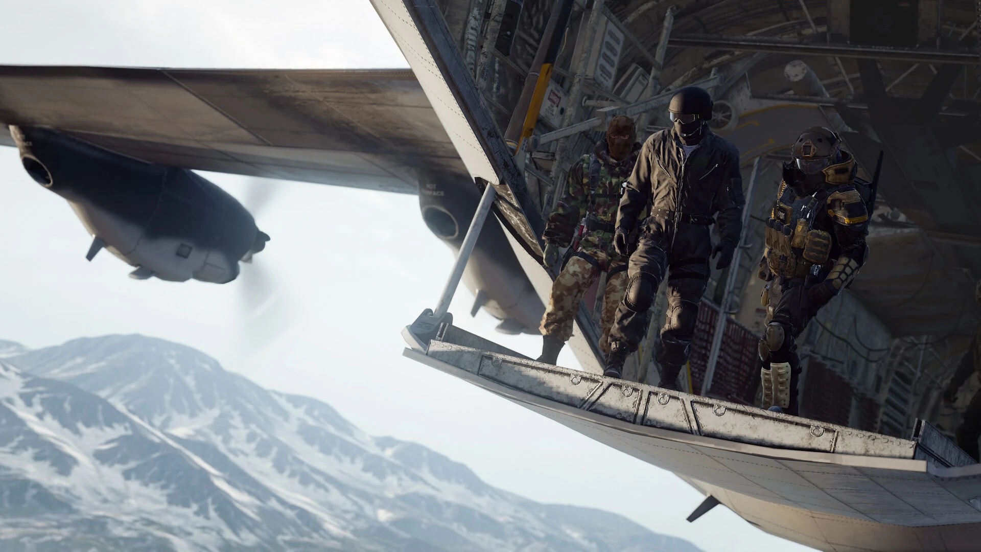 Three soldiers in tactical gear standing at the open cargo ramp of a military aircraft over snowy mountains.