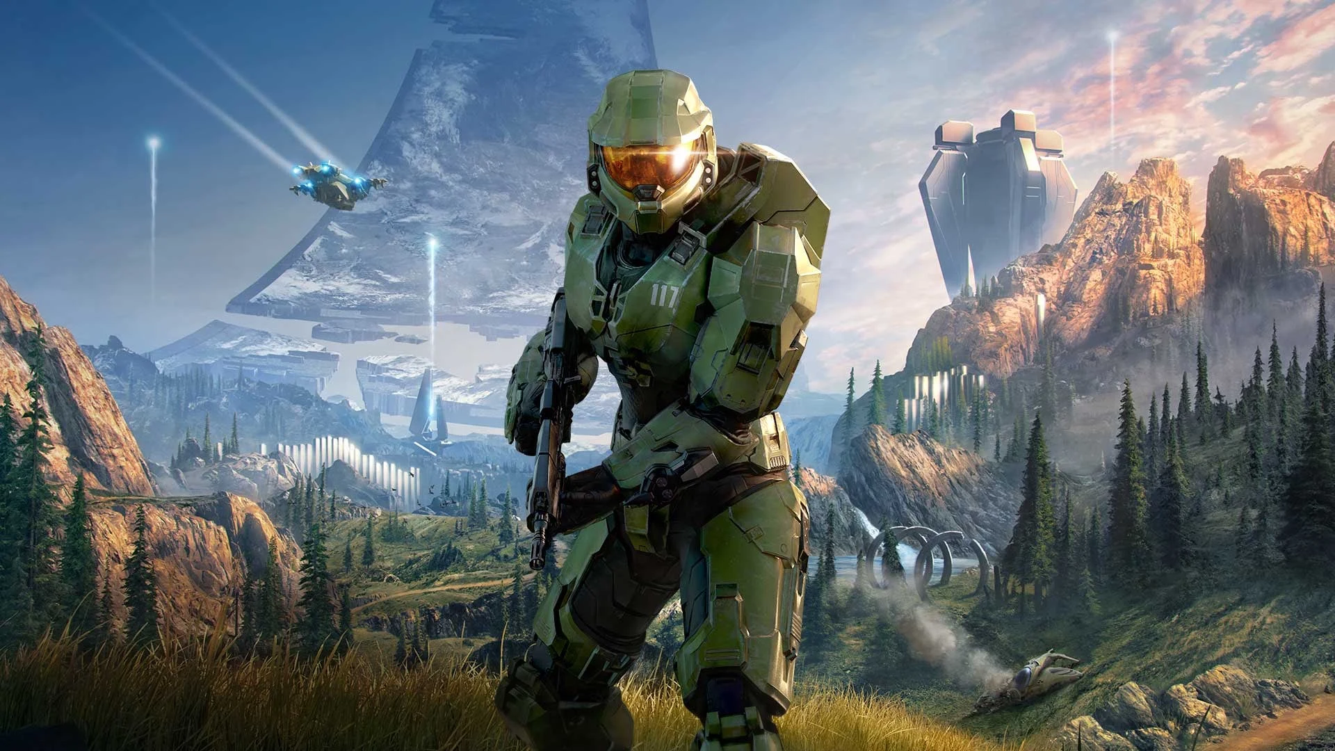 Master Chief in green armor standing in a mountainous landscape with alien structures in the background.