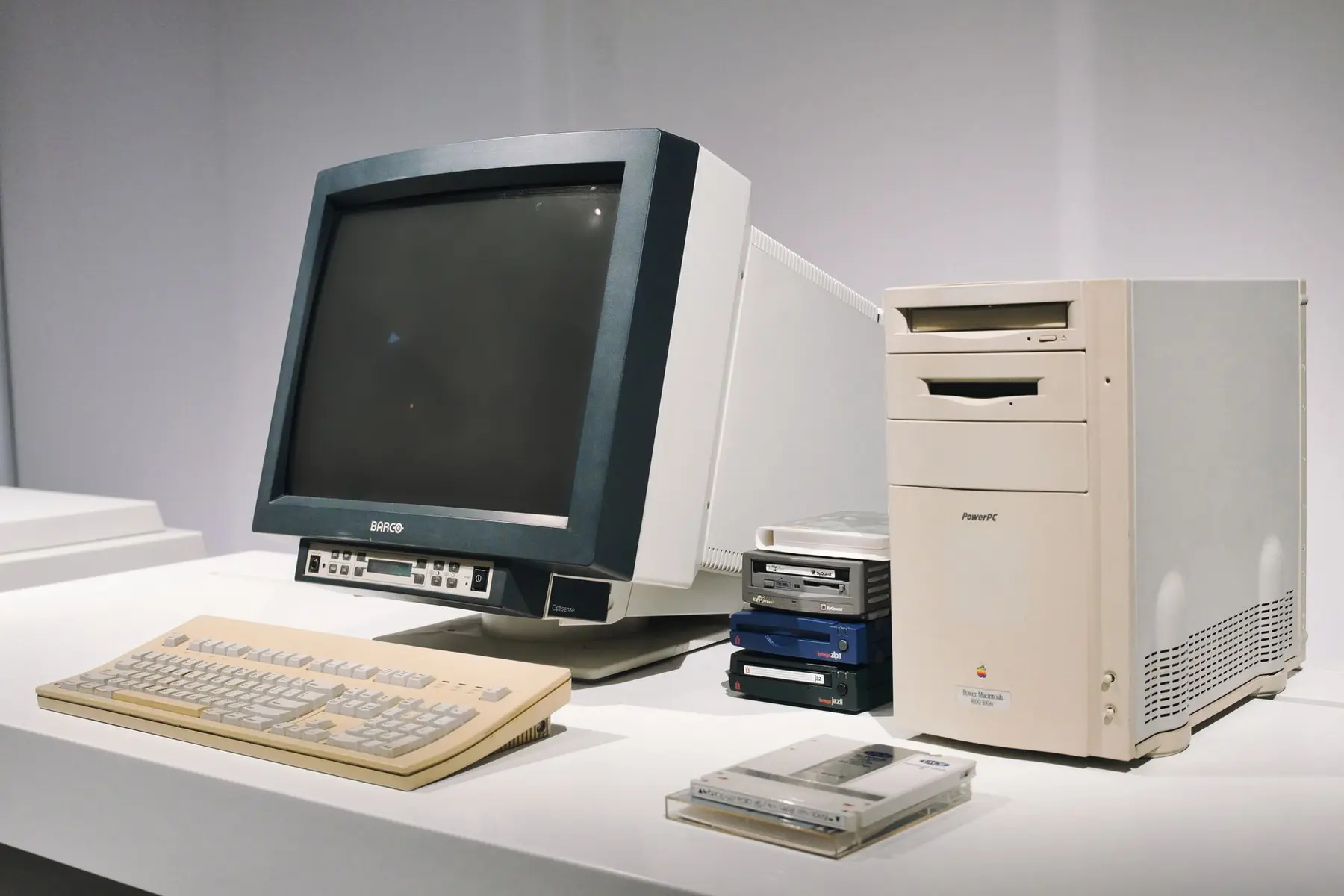 Vintage beige PowerPC Macintosh computer with a Barco CRT monitor, keyboard, and floppy disks
