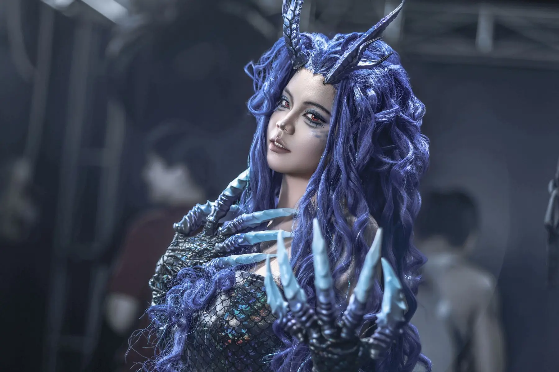 Cosplayer dressed as Xal'atath from World of Warcraft with purple hair, horns, and clawed gauntlets